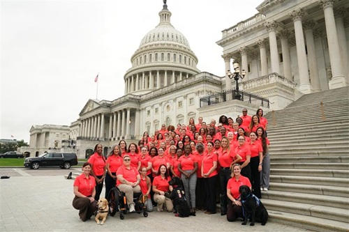 Large group in matching red shirts gathered on the U.S. Capitol steps.