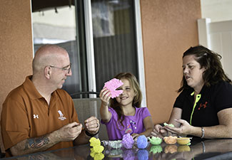 Two married veterans sit at a table with their daughter. The couple reconnected through couples Project Odyssey.