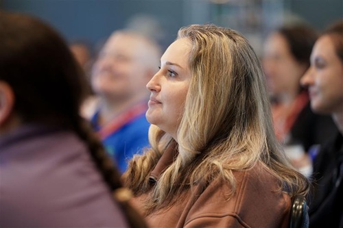 Jessica Roza seated among a group of attendees during an indoor event.