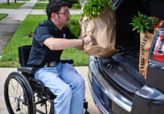wounded warrior unloading groceries from back of car in a wheelchair