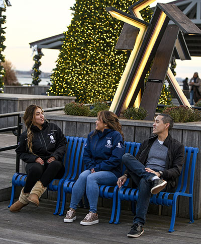 Three wounded warriors and veterans engaged in conversation in front of a Christmas tree.