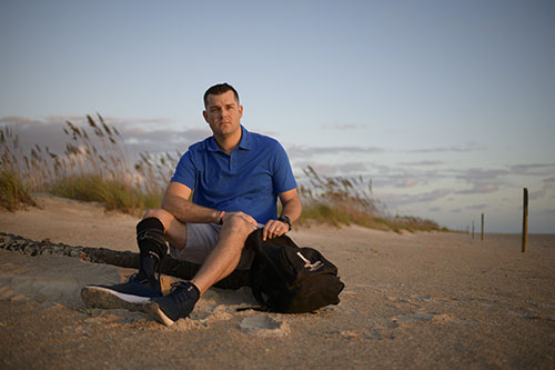 A warrior sitting on a rock with a WWP backpack.